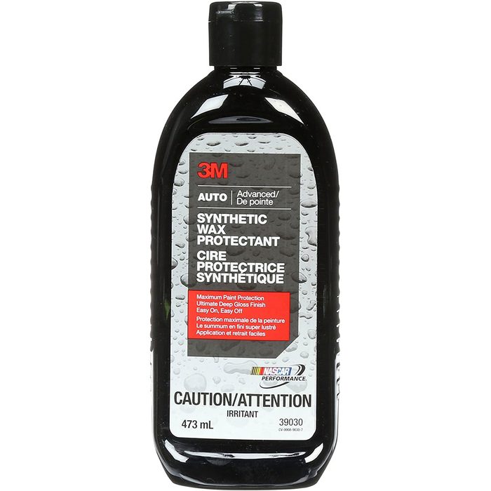 A black plastic bottle containing synthetic wax protectant stands upright, labeled with product details and safety cautions, suggesting use for automotive paint protection.