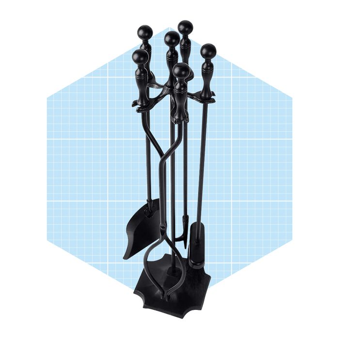 A black fireplace tool set stands upright, with tools for tending a fire, situated against a light blue grid background.