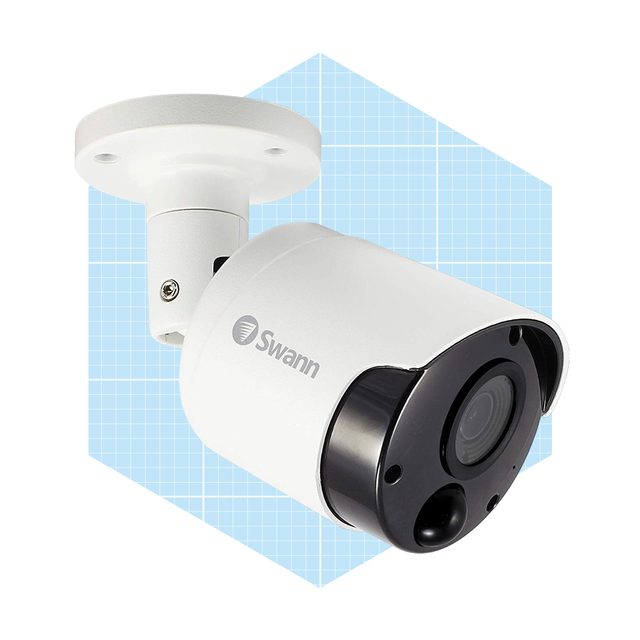 A security camera is mounted on a wall, designed to capture video footage. It features a white body with a black lens, against a blue grid backdrop.
