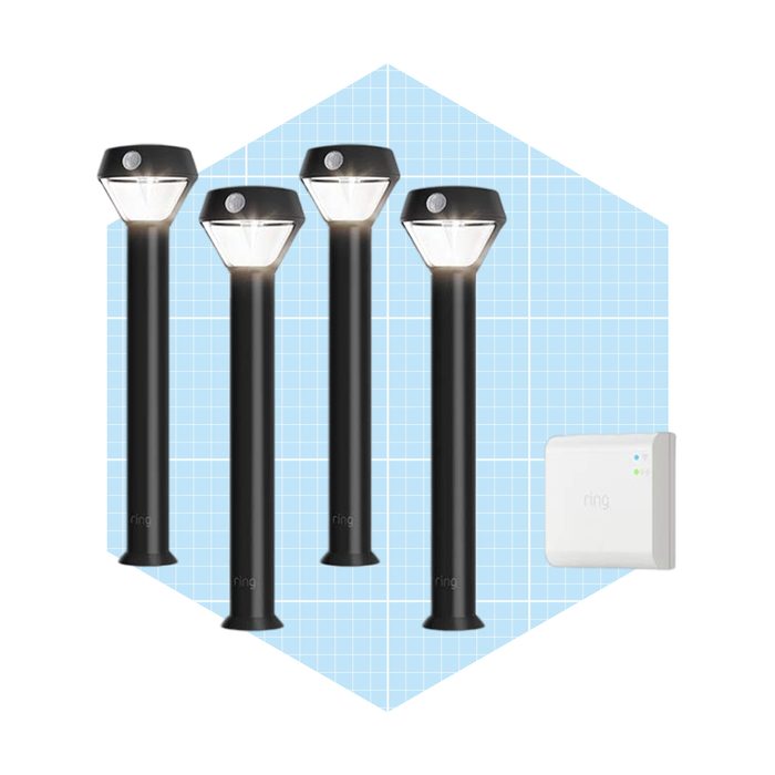 Four black outdoor lights stand upright, illuminating their surroundings, accompanied by a small white device on the side, set against a blue grid background.