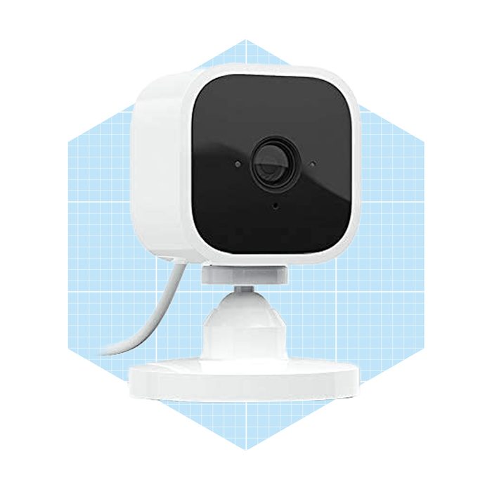 A square white camera with a black lens sits on a circular base, connected by a cable, against a light blue grid background.