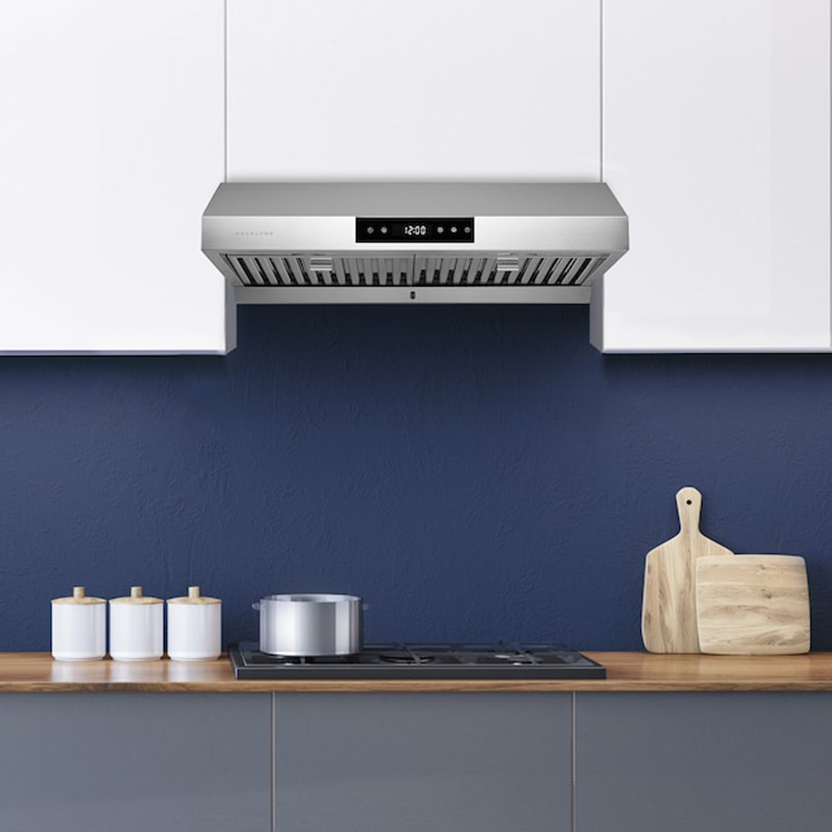 A stainless steel range hood hovers above a stovetop, where a pot simmers. The setting features navy walls, wooden countertops, and white storage jars.
