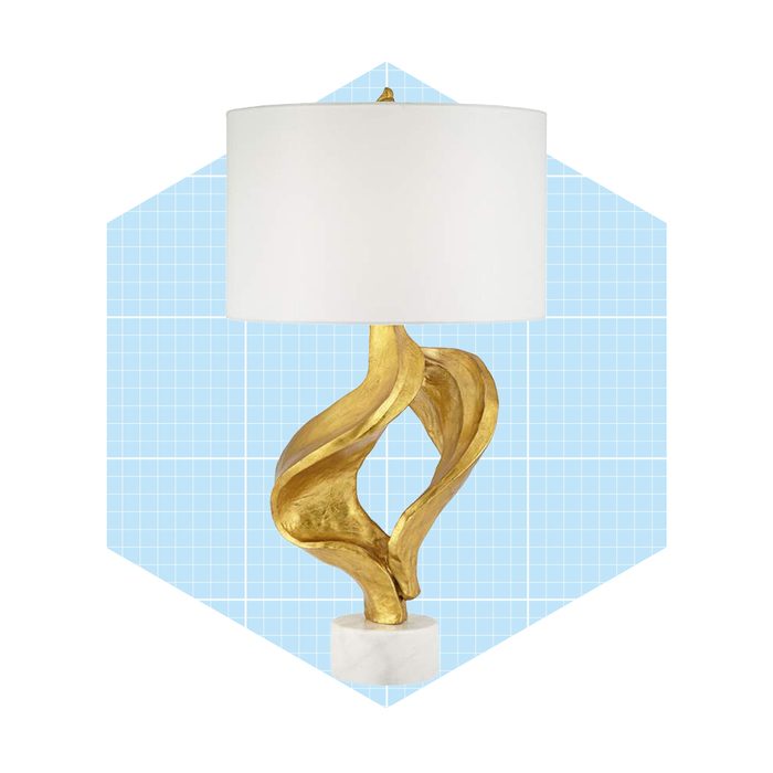 A decorative lamp with a twisting gold base illuminates a room, standing on a white marble pedestal against a light blue grid background.
