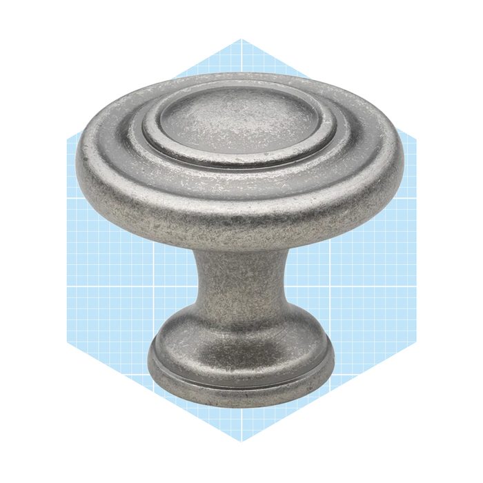 A metallic cabinet knob sits atop a light blue, grid-patterned background, designed for gripping and pulling, typically used on doors and drawers.