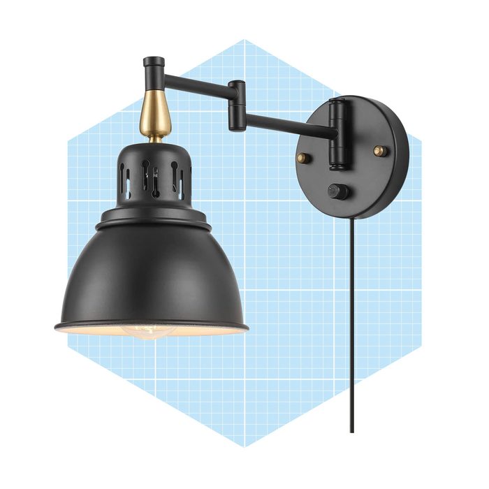 A black wall-mounted lamp with a metallic shade is positioned against a blue grid background, providing illumination through a visible bulb.