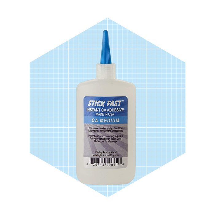 A bottle of Stick Fast instant adhesive stands upright, with a blue cap and label, set against a light blue grid background.