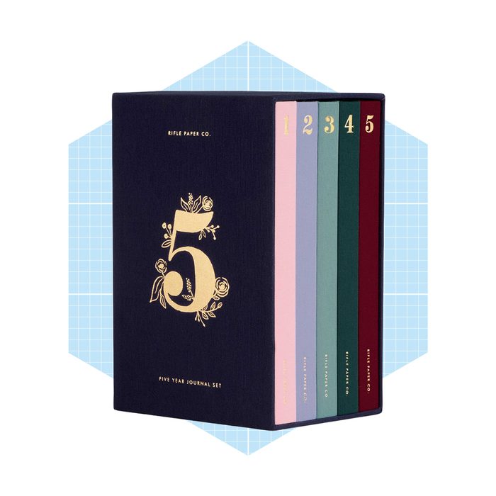 A five-year journal set, featuring five colorful journals, is displayed in a navy blue box with a floral number 