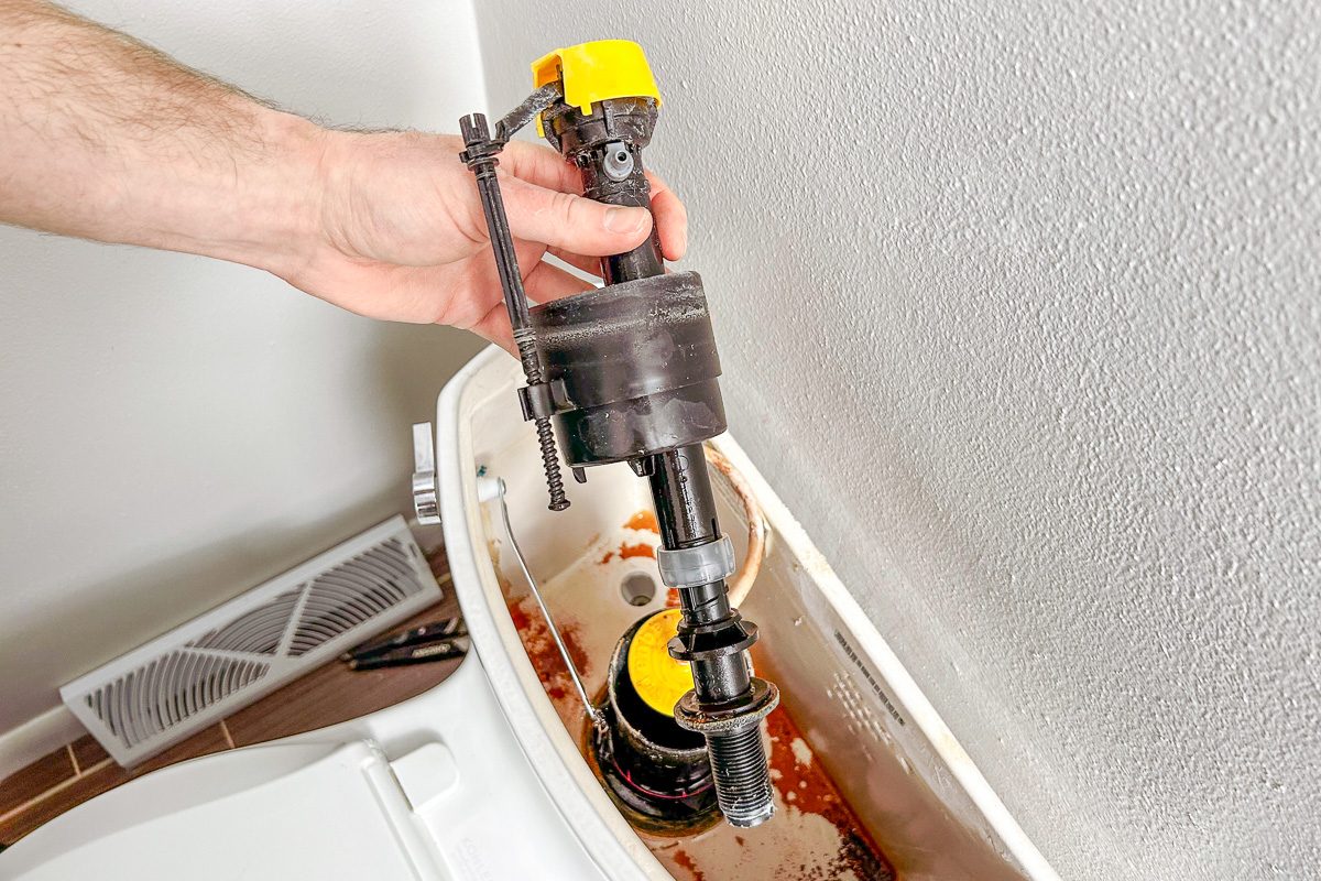 Hand holding Fill Valve over toilet tank